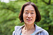 Senior Asian woman looking at the camera while standing outdoors