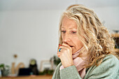 Ill senior woman putting hand on mouth while coughing