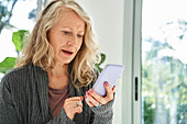 Ältere Frau prüft E-Mail-Posteingang auf dem Smartphone