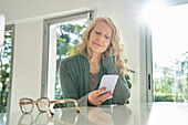 Senior woman using smart phone while sitting at counter