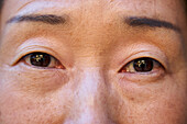 Nahaufnahme der Augen einer älteren asiatischen Frau, die in die Kamera schaut