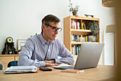 Senior businessman sitting at desk while using laptop