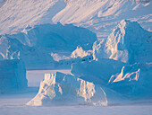Icebergs frozen into the sea ice of the Uummannaq Fjord System during winter. Background is Nuussuaq Peninsula, Greenland, Denmark.