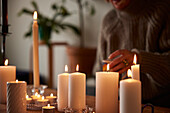 Frau sitzt zu Hause mit brennenden Kerzen