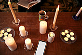 Smart phone and lit candles on table