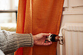 Woman turning radiator thermostat