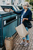Frau wirft Pappe in die Recyclingtonne