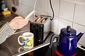 Hands holding cell phone over kitchen worktop