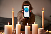 Frau zündet Kerzen an und nutzt die Temperatur-App