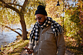 Mann benutzt Telefon im Herbstpark