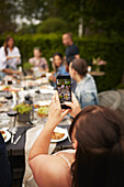 Woman photographing friends at table