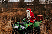Mann im Weihnachtsmannkostüm fährt Rasenmäher