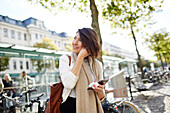 Smiling businesswoman using smart phone and earphones