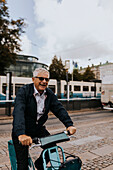 Lächelnder älterer Mann fährt mit dem Fahrrad in der Stadt