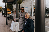 Älteres Paar wartet an der Bushaltestelle