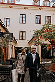 Senior couple with shopping bags walking by restaurant