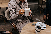 Ältere Frau hält Kaffeetasse in einem Café