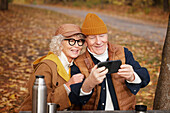 Senior couple taking selfie in park