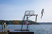 Teenage boys jumping into water from jumping tower