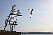 Jugendlicher, der vom Sprungturm ins Wasser springt
