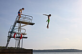 Teenage boys jumping into water from jumping tower