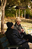 Smiling man talking to friend on bench