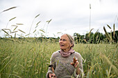 Ältere Frau geht in einem Feld spazieren