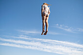 Mädchen springt gegen blauen Himmel