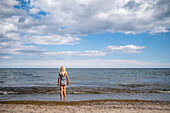 Girl standing on beach and looking at sea