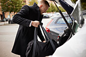 Man loading bag into car trunk