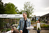 Smiling man holding empty plates in garden