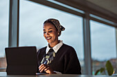 Lächelnde junge Frau arbeitet an einem Laptop