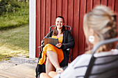 Smiling woman sitting in front of wooden house