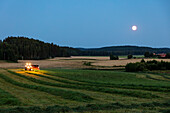 Farm machine working on farm at dusk