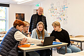 Teenager und Lehrer benutzen Laptop im Klassenzimmer