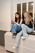 Teenage girls using phones at school