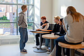 Teenager sitzen und reden auf dem Schulflur