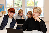 Teenage boys using laptops in classroom