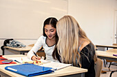 Teenage girls taking notes in classroom