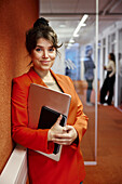 Portrait of smiling businesswoman standing in office corridor
