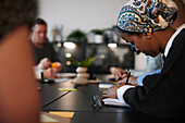Woman writing during business meeting