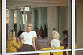 Geschäftsfrau schaut während einer Besprechung durch ein Bürofenster