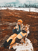 Frau sitzt mit Hund im Winter