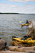 Man in yellow kayak paddling to shore