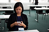 Geschäftsfrau sitzt am Schreibtisch und benutzt ein Smartphone