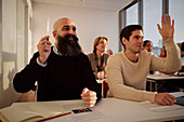 Group of adults sitting in class and raising hands