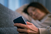 Woman lying down and holding smartphone