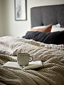 Mug and open book on bed