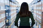 Woman looking through window at residential buildings