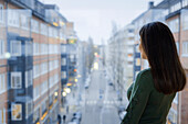 Woman looking through window at street